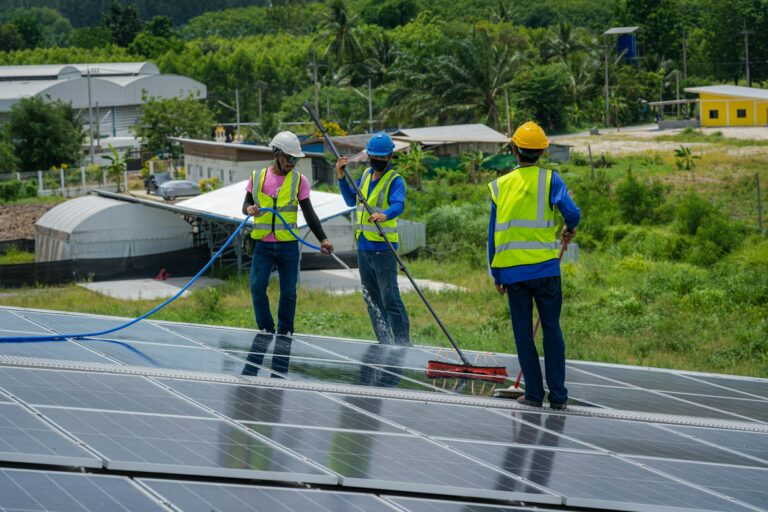 professional-worker-cleaning-solar-panels-with-brush-and-water-on-roof-structure-.jpg